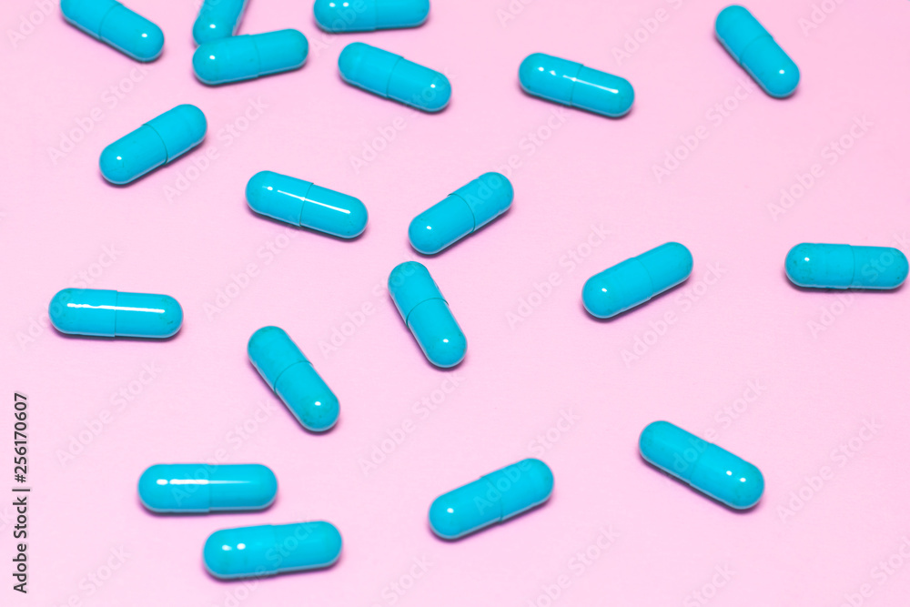 Bright blue pills on pink background close up Bright blue pills on pink background close up