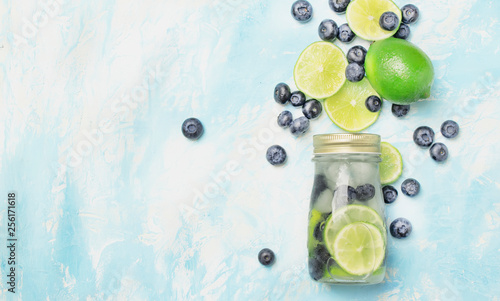 Summer cold drink with blueberry, lime and ice in glass bottle, top view
