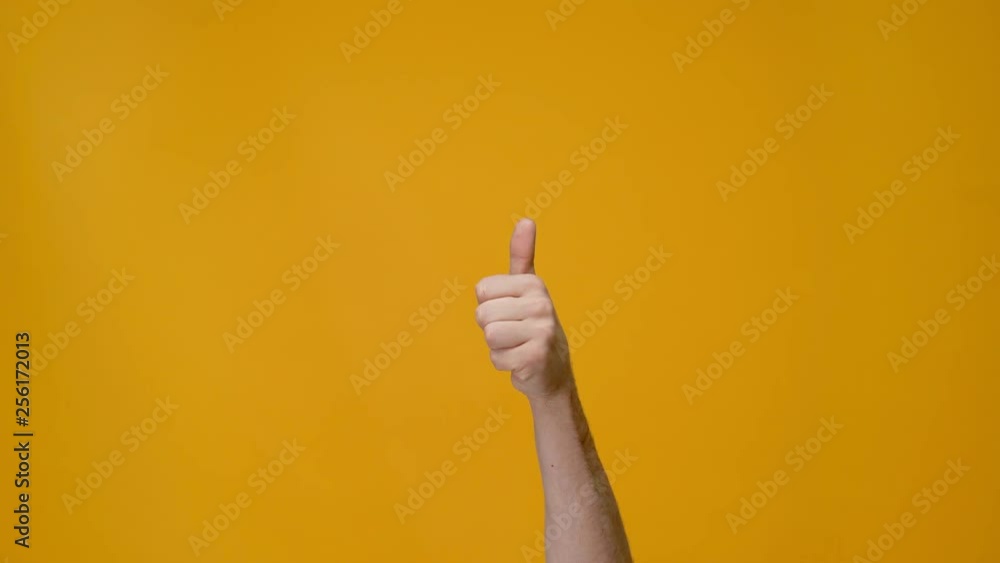 cropped view of man showing thumb up sign isolated on yellow cropped view of man showing thumb up sign isolated on yellow