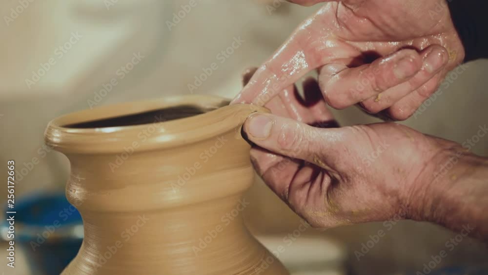 Potter's hands making top contour of clay pitcher in workshop Potter's hands making top contour of clay pitcher in workshop