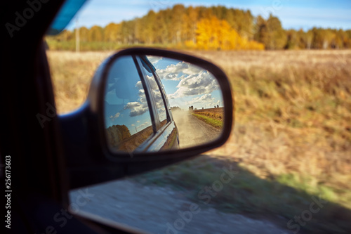View of a country road through the rearview mirror