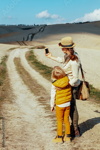 fit mother and child tourists taking selfie with smartphone