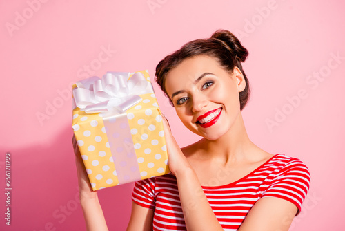Close-up portrait of her she nice-looking cute charming attractive glamorous winsome cheerful cheery girl in casual striped t-shirt holding in hands gift isolated over pink pastel background