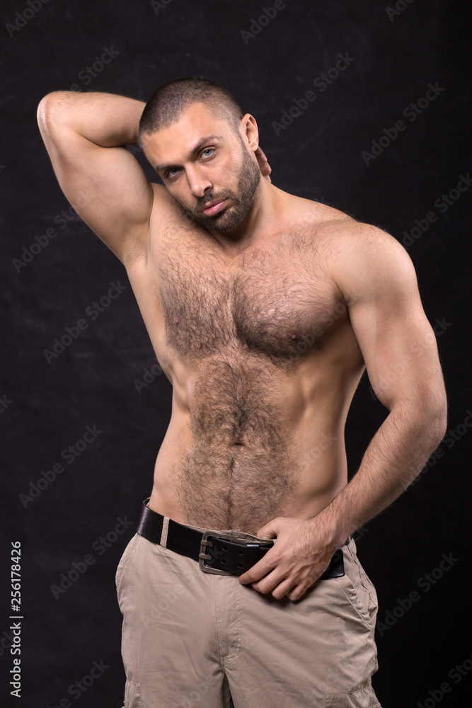 Brutal muscular topless man, in jeans. Bodybuilder relaxing standing.