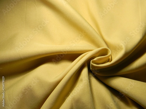 Ochre colored plain cotton wavy fabric. Texture, background. template. Lightweight fabric for curtains or bed linen. Poplin, coarse calico, staple, satin, chintz. Folds. Textile. Material. Mustard