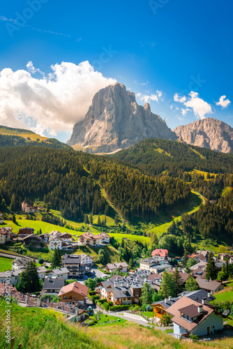 little rural town surrounded by forest and dolomites mountains during summer on a sunny day in south tyrol, italy