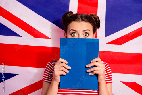 Close-up portrait of nice cute charming attractive funny afraid scared teen girl wearing striped t-shirt bachelor master degree hiding behind copy-book isolated over british flag background