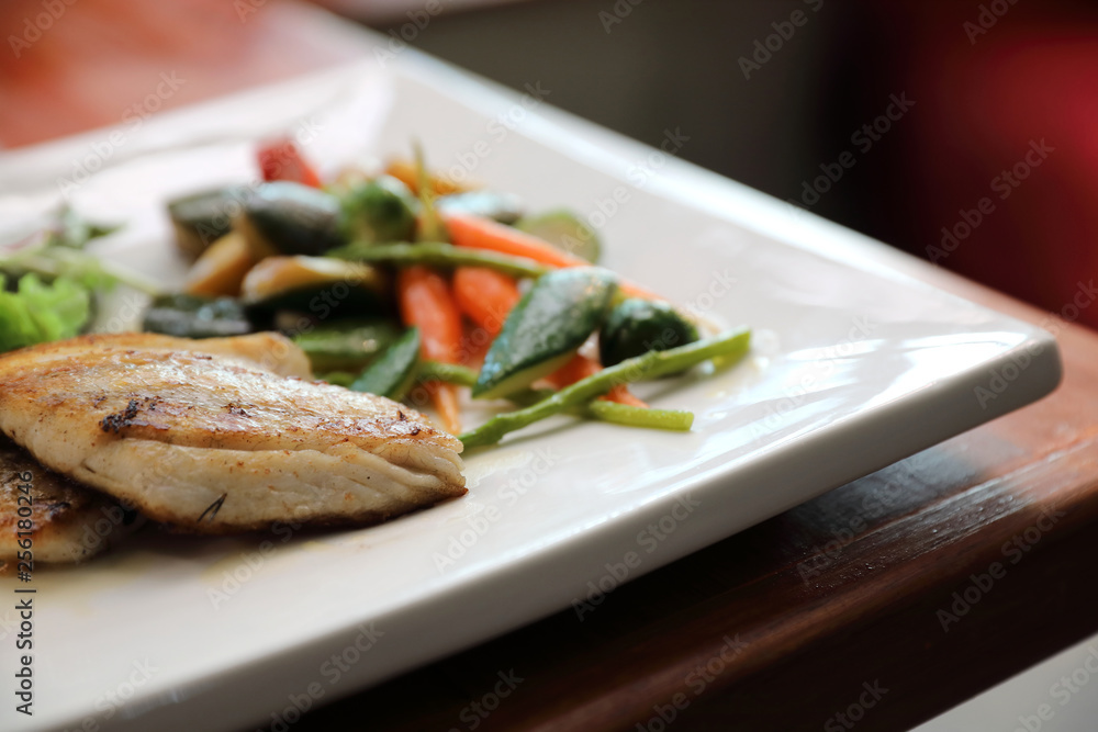 Sea bass fillet with grilled vegetables and salad on wooden table