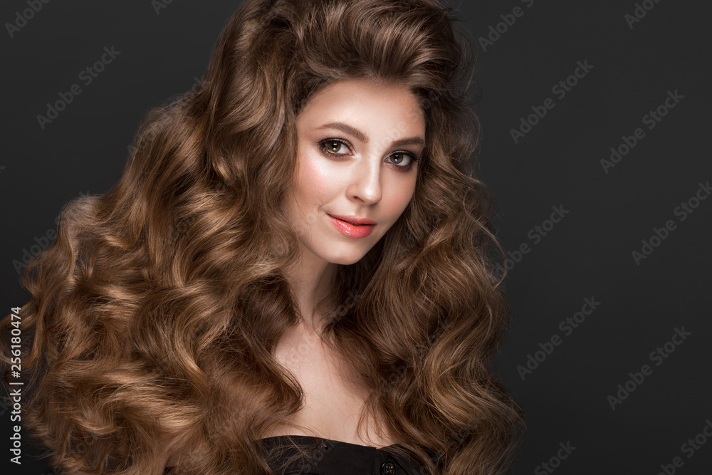 Fototapeta premium Beautiful brown-haired girl with a perfectly curls hair, and classic make-up. Beauty face.