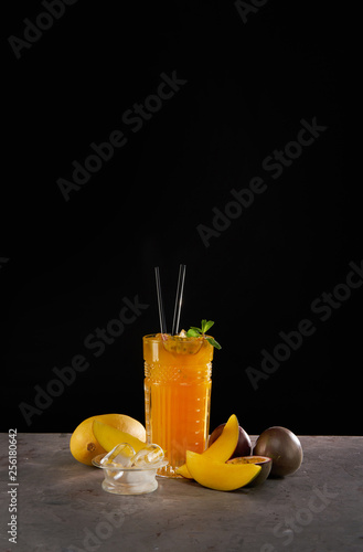 Fresh cocktail with mango, mint, passion fruit and ice. Alcoholic, non-alcoholic drink-beverage on black background