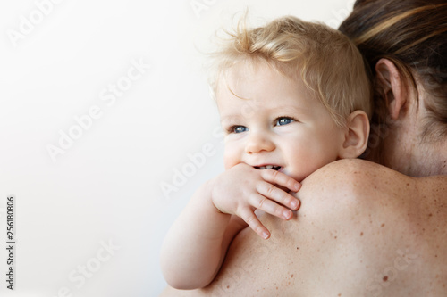 Smiling baby resting on mother's shoulder
