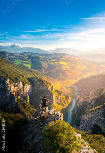 young man standing on top of cliff watching wonderful scenery in mountains during spring, colorful sunset in northern italy