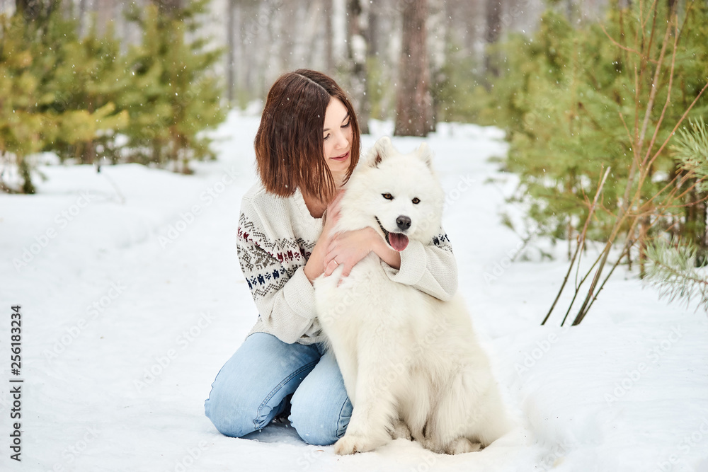 Girl in the winter forest walking with a dog. Snow is falling Girl in the winter forest walking with a dog. Snow is falling