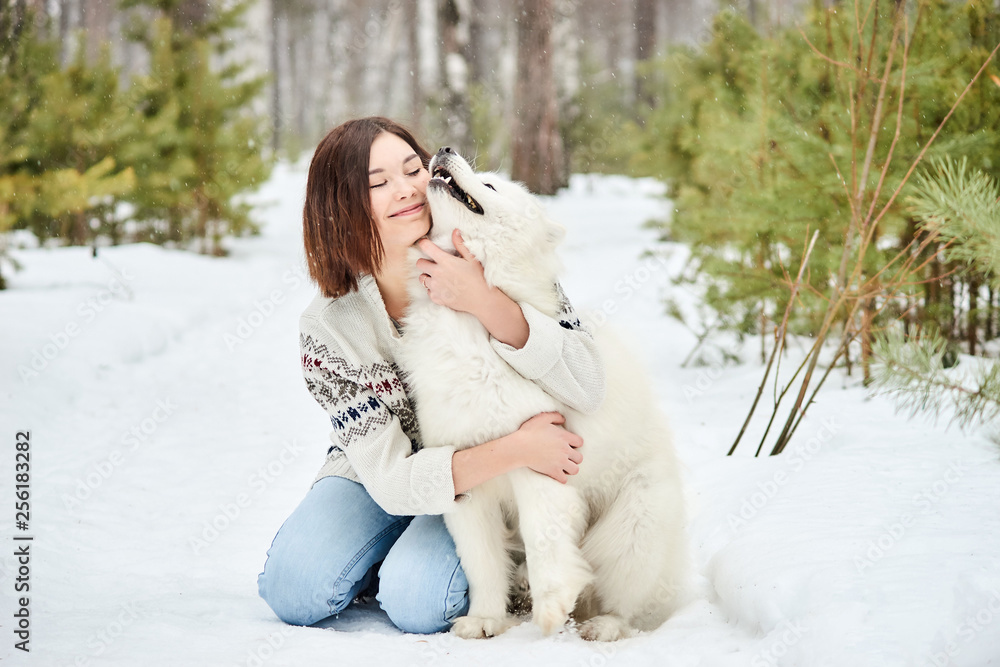 Girl in the winter forest walking with a dog. Snow is falling Girl in the winter forest walking with a dog. Snow is falling