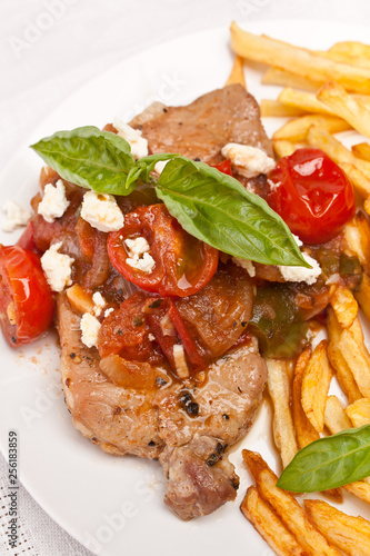 Pork chops with tomato, onion, garlic and feta sauce garnished with french fries