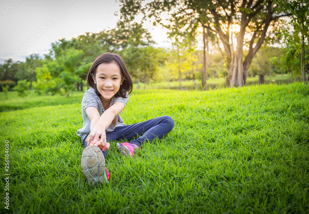 Asian little girl exercising at the outdoor park on the lawn is a meditation practice,child exercise in nature in the morning,healthy lifestyle concept Asian little girl exercising at the outdoor park on the lawn is a meditation practice,child exercise in nature in the morning,healthy lifestyle concept