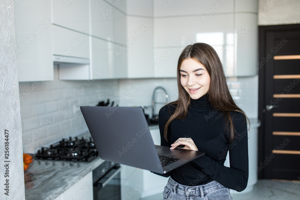 Young woman with her notebook in the kitchen Young woman with her notebook in the kitchen