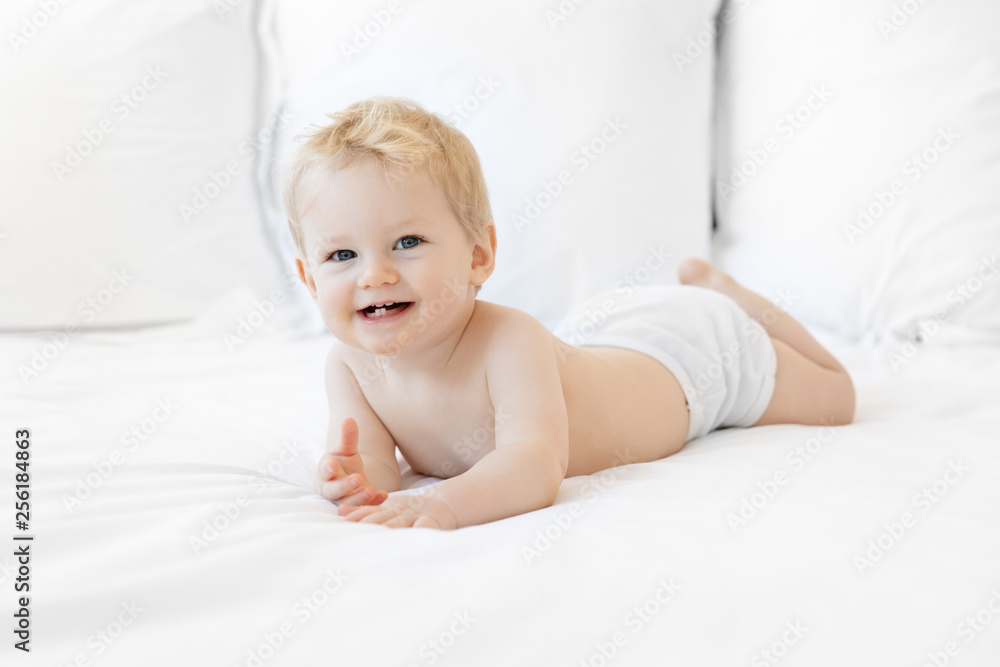 Happy blonde baby boy lying on belly wearing diaper Happy blonde baby boy lying on belly wearing diaper