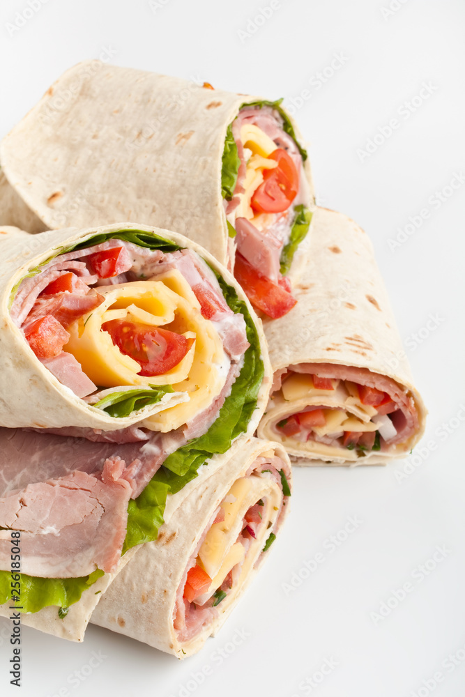 stack of wrapped tortilla sandwich rolls cut in half on white background stack of wrapped tortilla sandwich rolls cut in half on white background