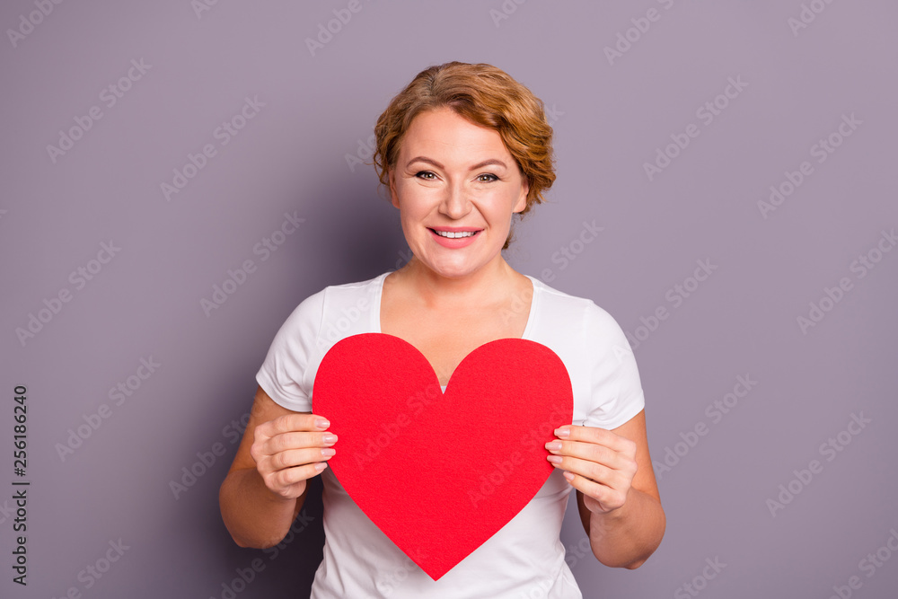 Portrait of nice cute lovely attractive sweet cheerful cheery wavy-haired lady in casual white t-shirt holding in hands heart isolated on gray violet purple pastel background Portrait of nice cute lovely attractive sweet cheerful cheery wavy-haired lady in casual white t-shirt holding in hands heart isolated on gray violet purple pastel background