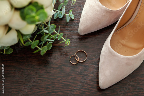 Beautiful wedding bouquet of flowers rings bridal shoes on wooden background. Declaration of love, spring. Wedding card, Valentine's Day greeting. Wedding rings. Wedding day details