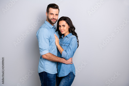 Bonding person. Portrait of attractive peaceful cheerful handsome married students cuddling isolated wearing denim clothing on ashy-gray background