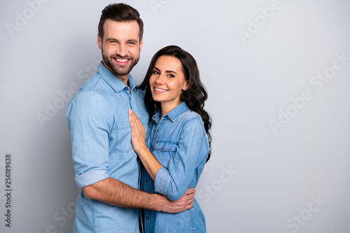 Together forever. Portrait of handsome charming married people spouses isolated feeling cheerful joyful wearing denim shirts on silver background