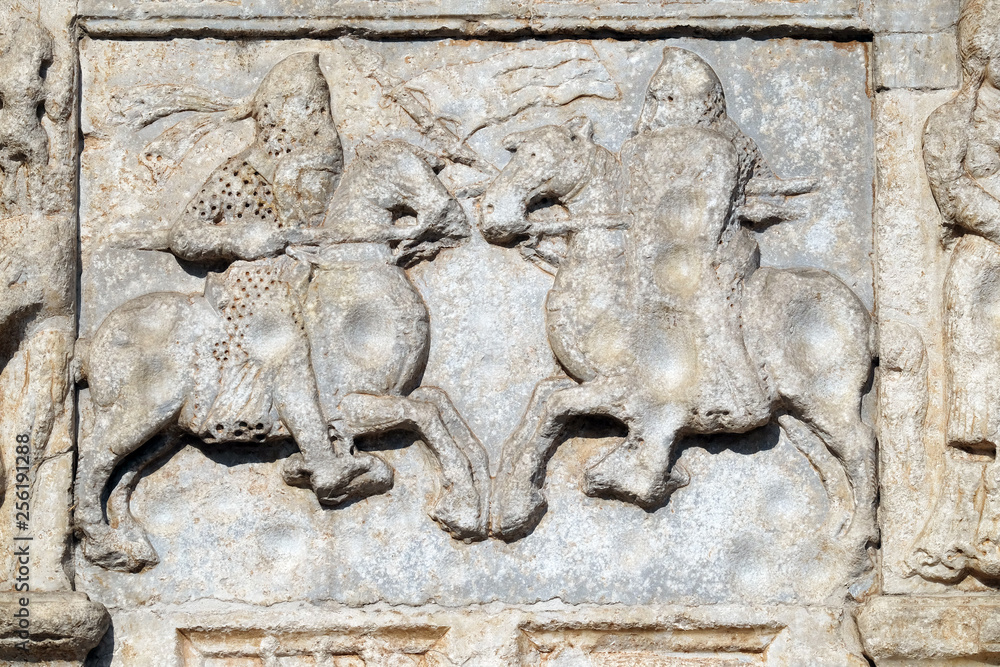 Knights fight horseback with lance and shield, medieval relief on the facade of Basilica of San Zeno in Verona, Italy