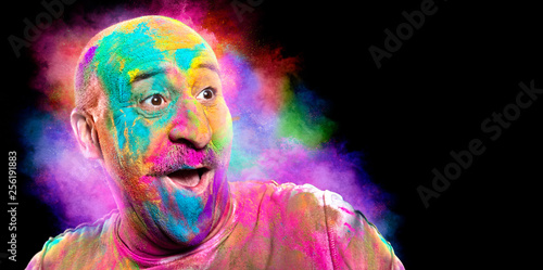 Bald smiling man with colorful face having fun. Holi color festival