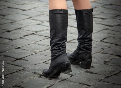 The legs of the girl in boots on the pavement