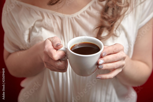 White cup of black coffee in female hands
