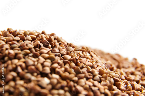 Heap of buckwheat grains. Dry brown kernel on white background. Selective focus