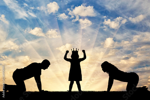 Silhouette of a child girl with a crown on her head and parents worshiping her