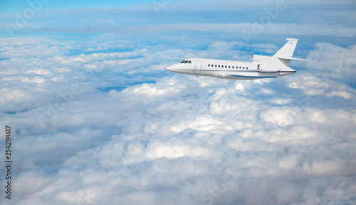 Luxury design private jet flying over the clouds and sea 