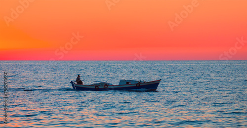 A fisherman departs Alanya Harbor on the Mediterranean sea in Alanya at dusk  © muratart