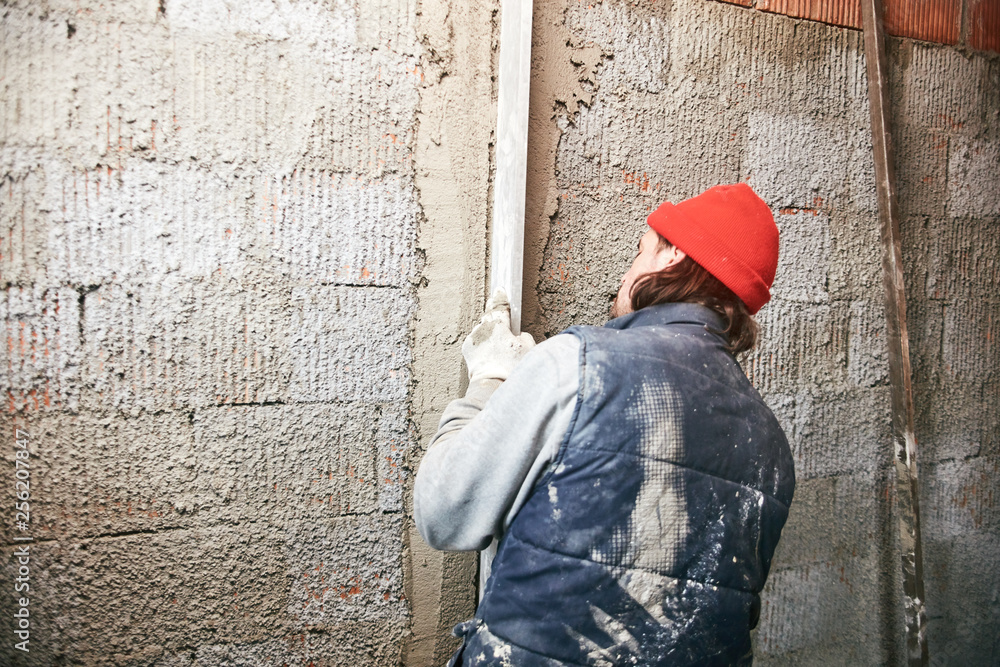 Real construction worker making a wall inside the new house.