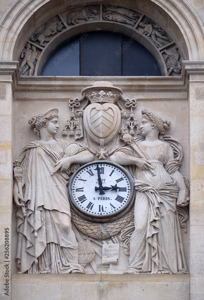 Two muses support the clock, topped by the coat of arms of Cardinal Richelieu, facade of the Saint Ursule chapel of the Sorbonne in Paris, France Two muses support the clock, topped by the coat of arms of Cardinal Richelieu, facade of the Saint Ursule chapel of the Sorbonne in Paris, France