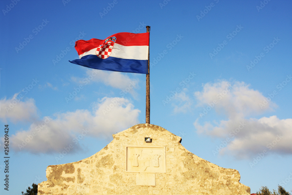 Croatia flag waving on the blue sky on the town Nin Gate.