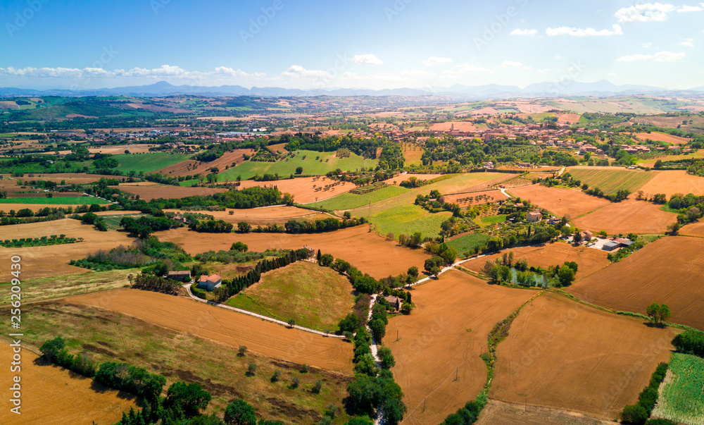 aerial view of countryside hills landscape with dry wheat fields and mountains in the distance  during summer