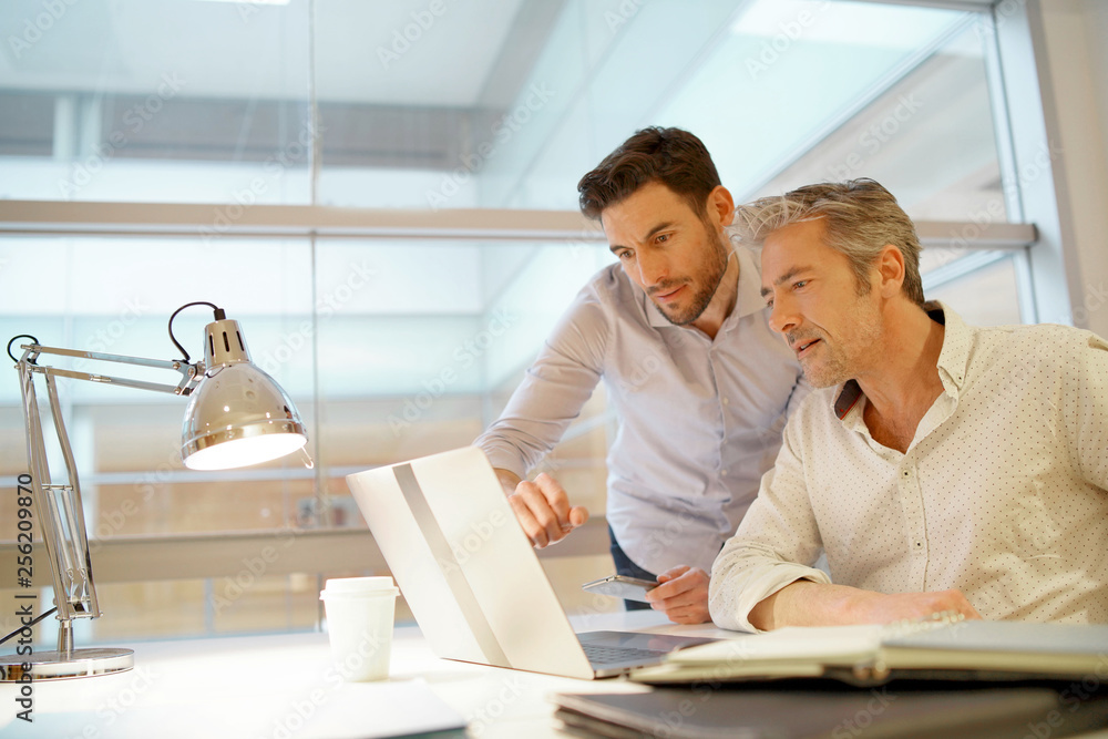 © goodluz - Male coworkers talking over ideas in modern office © goodluz - Male coworkers talking over ideas in modern office