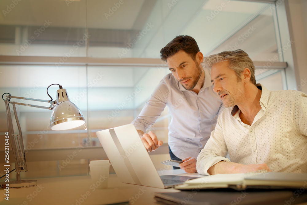 Male coworkers talking over ideas in modern office Male coworkers talking over ideas in modern office