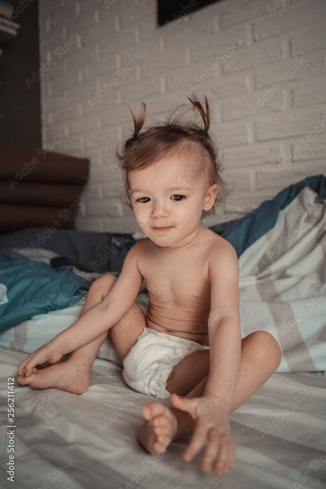 child with tails on his head favors morning in bed in his parents' room on a sunny day. concept of a family of typical, ordinary home-like recreation of a real middle-income family in Europe child with tails on his head favors morning in bed in his parents' room on a sunny day. concept of a family of typical, ordinary home-like recreation of a real middle-income family in Europe