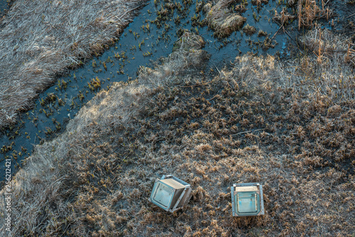 Top view on the stream or small river. There are dry grasses and two architectural lights. Aerial drone shot