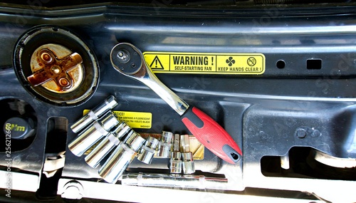 Tools on car engine bay. Tools with engine bay on background. Tools with yellow warning on background.