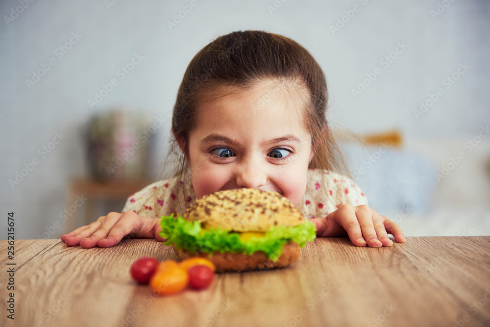 Playful girl looking at delicious hamburger Playful girl looking at delicious hamburger