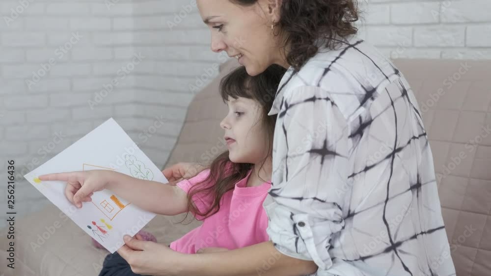 Mother looks at the drawing of the child. Mother looks at the drawing of the child.