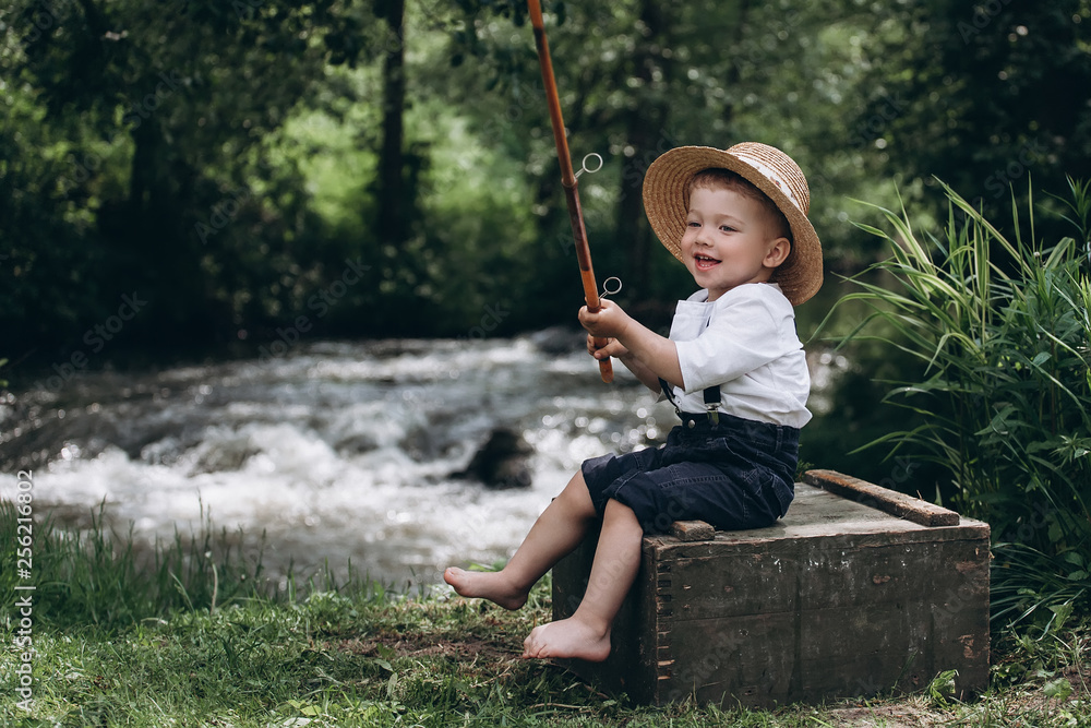 Portrait of cute caucasian blondie baby boy with fishing rod in