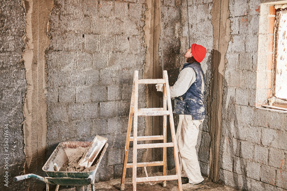 Real construction worker making a wall inside the new house. Real construction worker making a wall inside the new house.