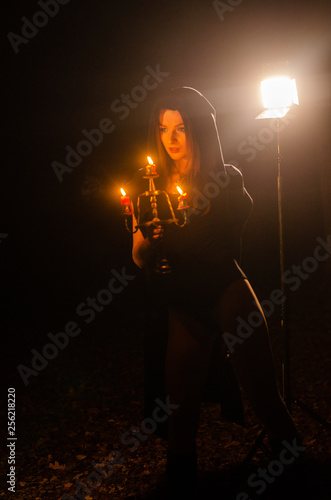 Young girl in a long black coat fire night.