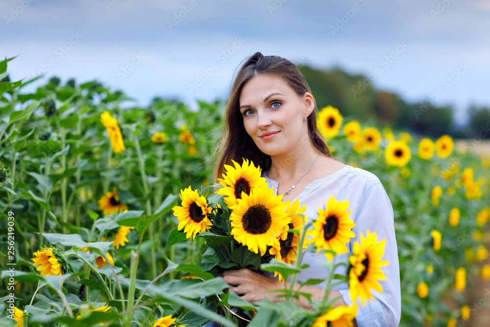 Beautiful young woman on sunflower field with bouquet flowers. Happy girl on summer sunset day. Beautiful young woman on sunflower field with bouquet flowers. Happy girl on summer sunset day.